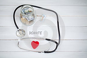 Donations and Charity. Inscription Donate. Donation Concept. Glass with Donations on White Background. Charity and Money