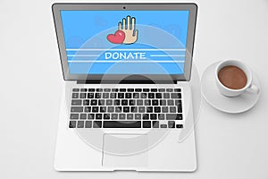 Donations. Modern laptop and cup of coffee on white table