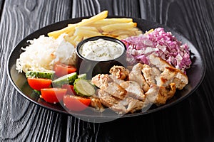 Doner kebab on a plate with french fries, salad and sauce close-up on a table. horizontal