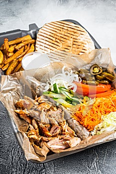 Doner kebab Shawarma on a plate with french fries and salad in box to go, take away. White background. Top view