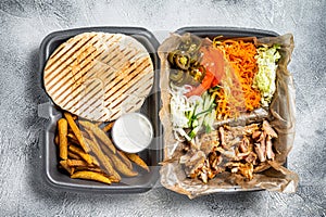 Doner kebab Shawarma on a plate with french fries and salad in box to go, take away. White background. Top view