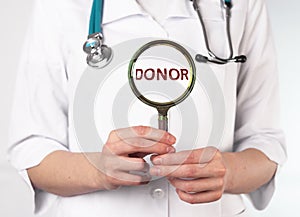 Donor word through magnifying glass. Blood and organ donation concept