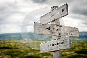 dont be useless text engraved on old wooden signpost outdoors in nature