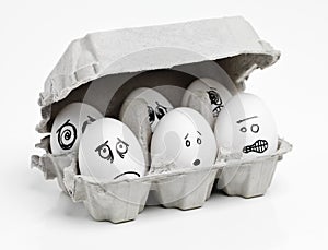 Dont close the lid, were afraid of the dark. Studio shot of faces drawn onto a carton of eggs.