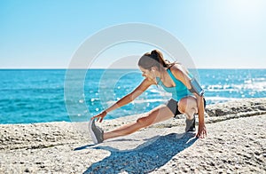 Dont ever doubt yourself. a young woman stretching while out on the beach on a sunny day.