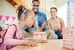 Dont forget to make a wish. a little girl celebrating a birthday with her parents at home.