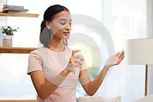 Dont forget to sanitise. a young woman sanitising her hands at home. photo