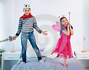 We dont get along all the time. Portrait of two young children dressed up as superheroes jumping on a bed at home.