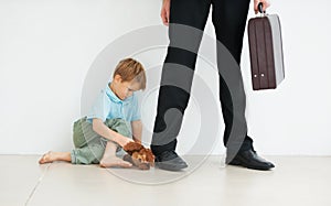 Dont go.... A young boy holding a teddybear and looking sad because his dad has to go to work.