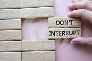 Dont interrupt symbol. Concept word Dont interrupt on wooden blocks. Businessman hand. Beautiful pink background. Business and photo