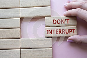 Dont interrupt symbol. Concept word Dont interrupt on wooden blocks. Businessman hand. Beautiful pink background. Business and photo