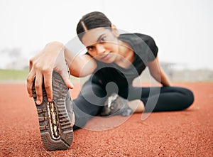 Dont just touch your toes, reach for your dreams. an athletic young woman stretching while out on the track.