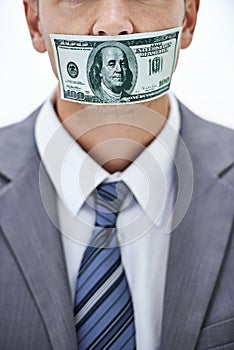 Dont say a word...A businessman with his mouth covered with paper money.