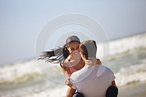 Dont stop spinning my world around. a young couple being playful on the beach.