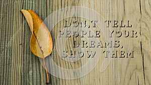 Dont Tell People Your Dream. Show Them sentence. Written on wooden surface. falling leaf