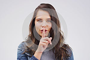 Dont tell them Im the one who told you. Portrait of an attractive young woman posing with her finger on her lips against
