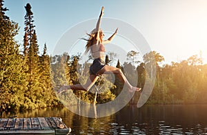 Dont think, just do. an attractive young woman jumping into a lake.
