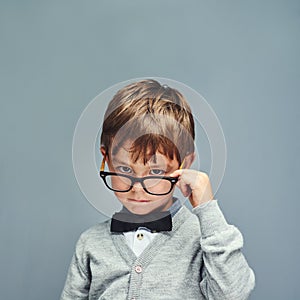 Dont waste my time. Studio portrait of a smartly dressed little boy posing with attitude against a gray background.