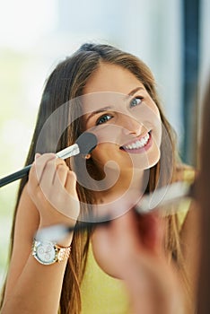 Dont you just love this new shade of blush. Portrait of an attractive young woman applying makeup to her face with a