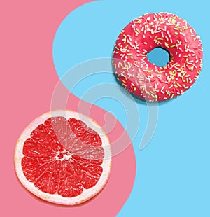 Donut on a blue background and pink grapefruit.