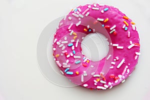 Donut coated with a pink frosting and sprinkles of different col