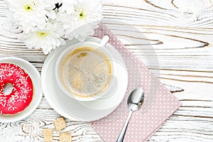 Donut and coffee, flowers on wooden background
