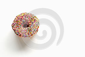 Donut with colorful sprinkles on white background with copy space