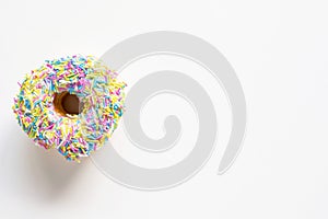 Donut with colorful sprinkles on white background with copy space