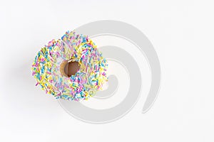 Donut with colorful sprinkles on white background with copy space