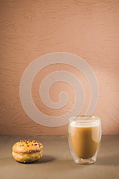 donut in glaze and a cappuccino glass/donut in glaze and a cappuccino glass on a brown background with copy space