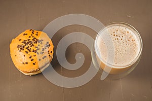 donut in glaze and a cappuccino glass /donut in glaze and a cappuccino glass on a brown background. Top view