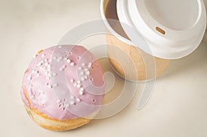 Donut in glaze and a paper coffee cup/donut in glaze and a paper