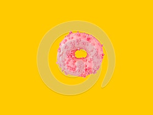 Donut glazed with pink strawberry icing sugar sprinkles floating in air on yellow background. Creative food poster