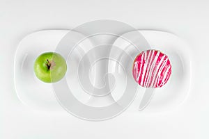 A donut and a green apple lie on the plates top view, the right choice. Concept Resistance to temptation, fast food, healthy food