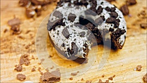 Donut has a mouth-shaped bite. Chocolate donuts decorated with pieces of oreo biscuits. Donuts are on a paper decorated