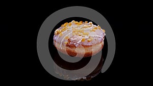 Donut with icing and orange peel sprinkle rotating on a black background.