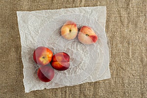 Donut Peaches also known as Saturn peaches and nectarine on a rustic canvas background. Healthy food concept.