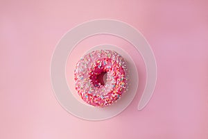 Donut with pink icing on a pink background top view. Junk food. Sweets, pastries. donut day