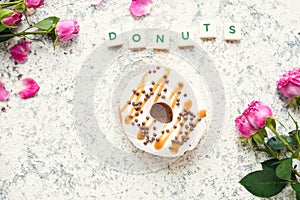 Donut with pink roses over light background