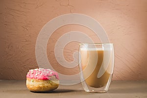 donut in red glaze and a cappuccino /donut in red glaze and cappuccino glass on a brown background