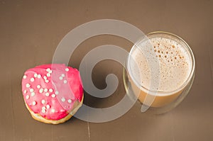 donut in red glaze and a cappuccino/donut in red glaze and cappuccino glass on a brown background. Top view