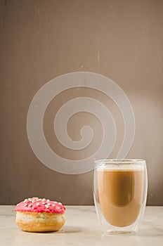 donut in red glaze and a cappuccino. donut in red glaze and a glass with a cappuccino on a dark background with copy space