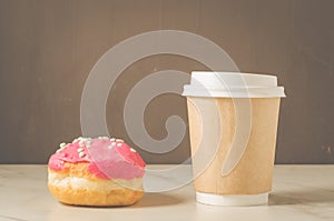 Donut in red glaze and a paper coffee cup/donut in red glaze and