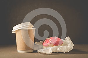 Donut in red glaze and a paper coffee cupdonut in red glaze and