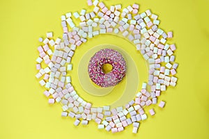 Donut in a round marshmallow frame on a yellow background. top view photo