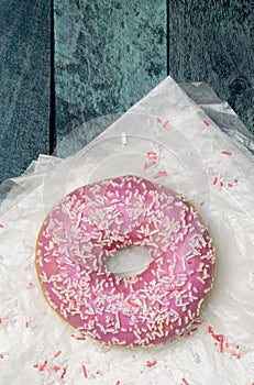 Donut with sugar sprinkles on a turquoise wooden background