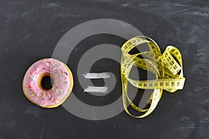 Donut and tailor measure tape on blackboard in sugar sweet abuse and addiction equal body overweight