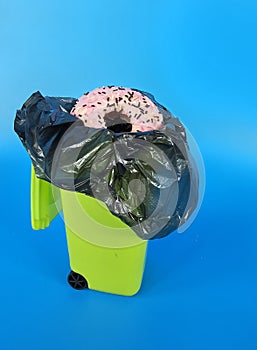 Donut is thrown into the trash bin. Refusal of high calorie foods concept