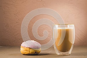 donut in violet glaze and a cappuccino glass/donut in violet glaze and a cappuccino glass on a brown background