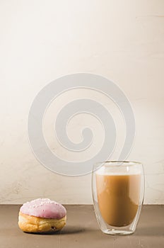 donut in violet glaze and a cappuccino glass/donut in violet glaze and a cappuccino glass on a white background with copy space